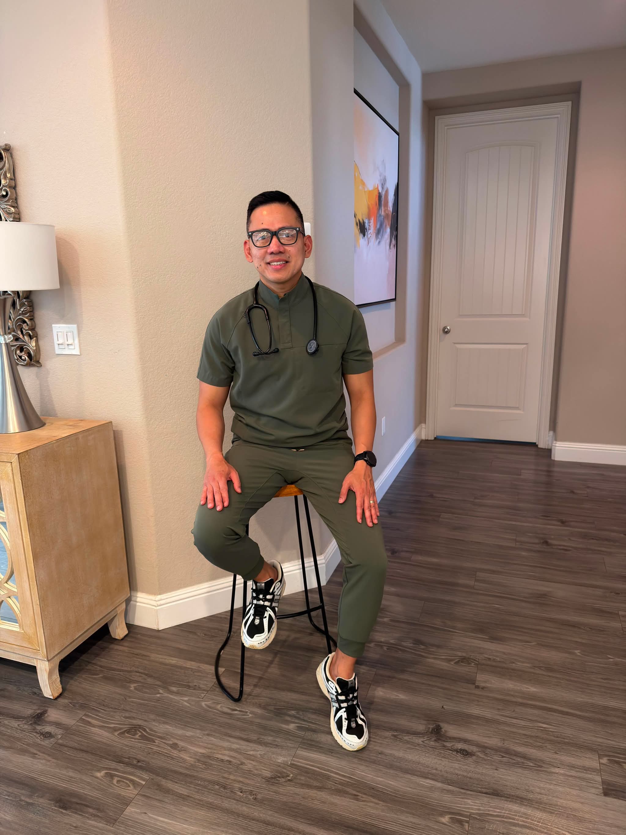 James Bonifacio seated in scrubs with a stethoscope